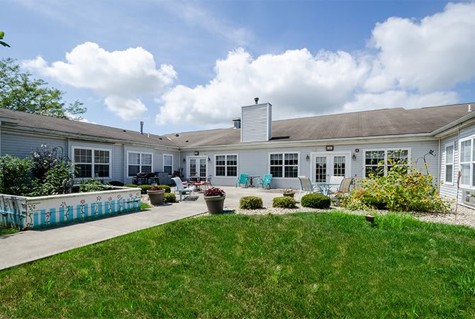 A spacious backyard with a patio and well-maintained lawn under a partly cloudy sky.