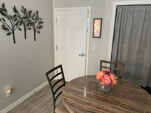 A cozy dining area with a round table, chairs, and decorative flowers, complemented by wall art and neutral tones.