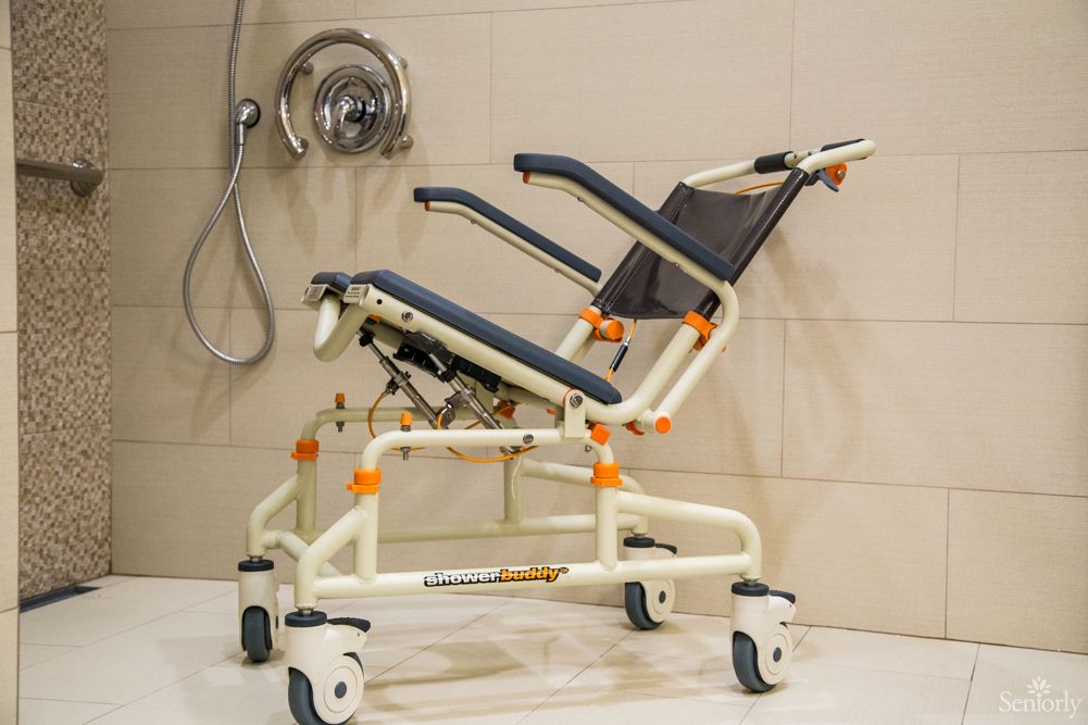 A tilting shower chair with wheels designed for accessibility in a bathroom setting.