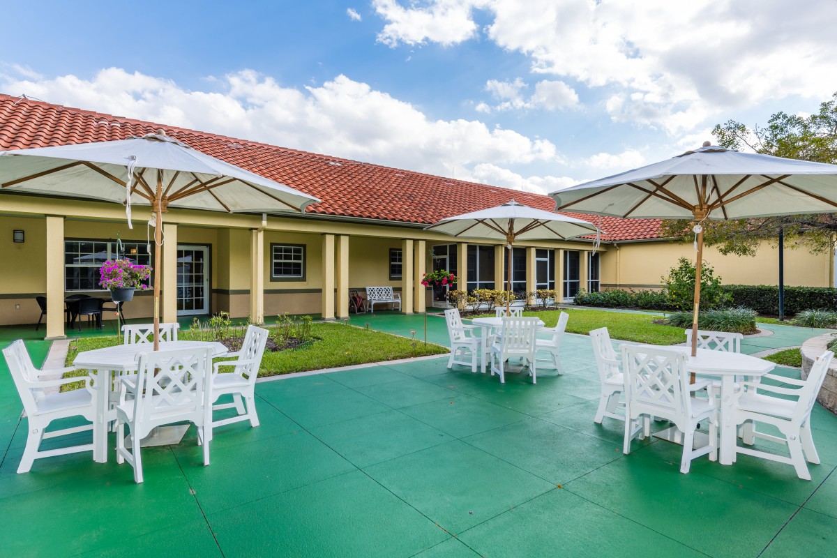 A sunny outdoor patio with tables and chairs in front of a building.