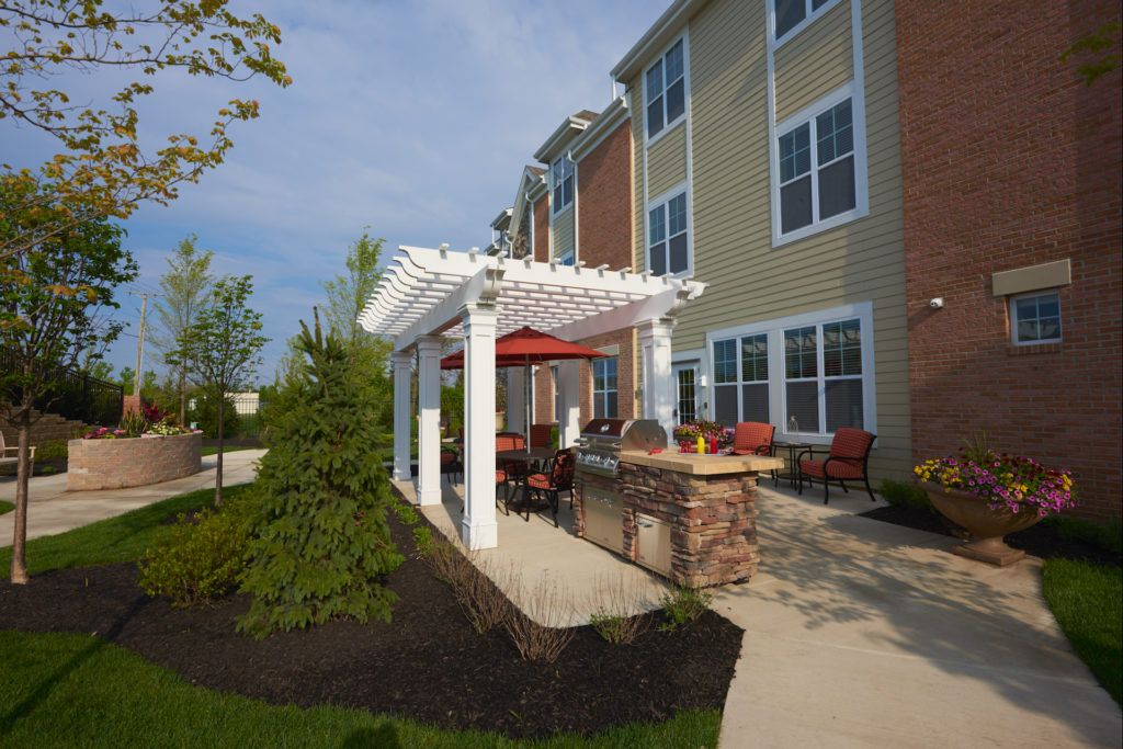 A cozy outdoor patio with a pergola and seating area next to an apartment building.