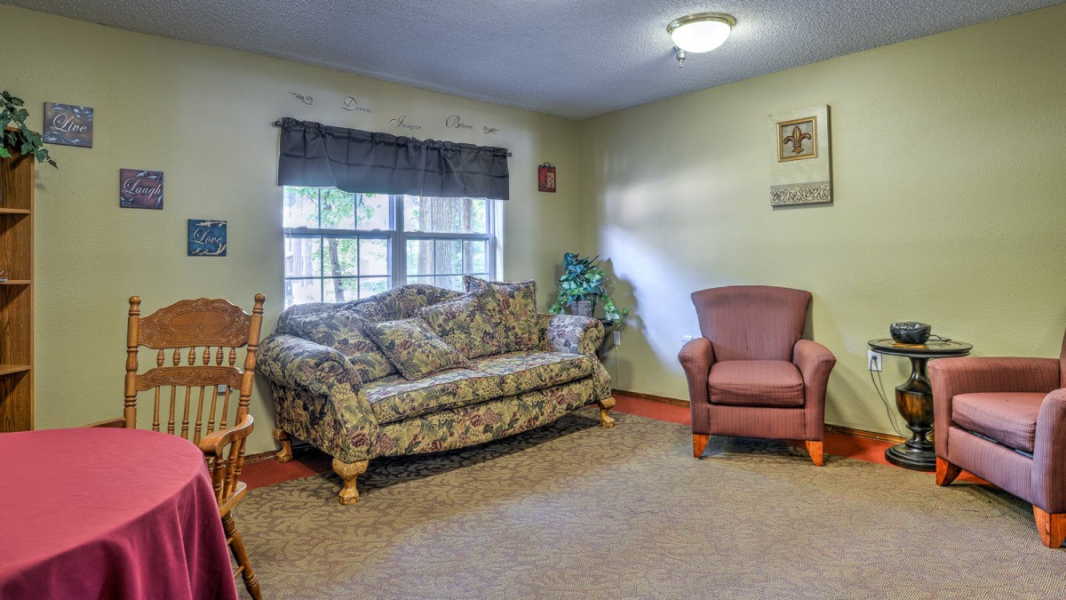 A cozy living room featuring a floral sofa and a red armchair, with ample natural light from the window.