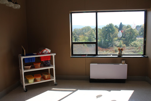 A well-lit room featuring a shelf with colorful containers and a large window offering a view of the outdoors.