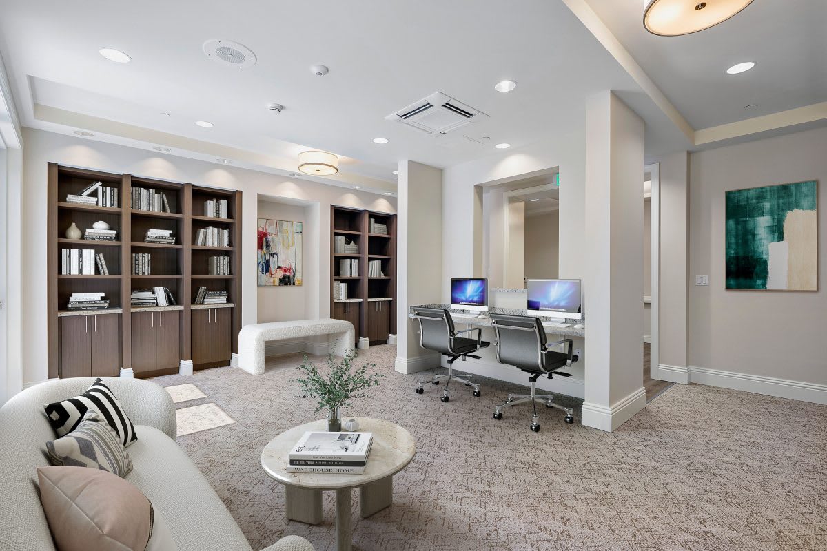 A modern office workspace featuring computers, bookshelves, and stylish furniture.