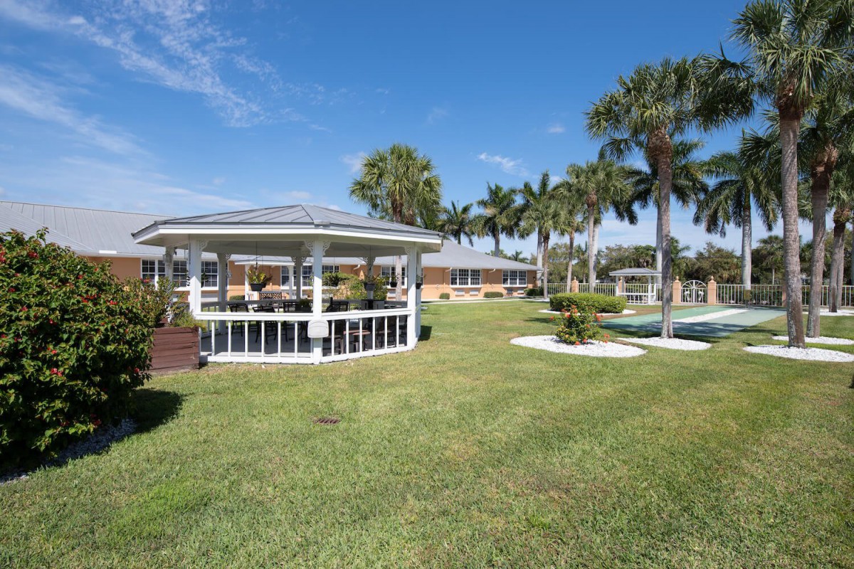 A sunny day at a well-maintained park with a gazebo and palm trees.