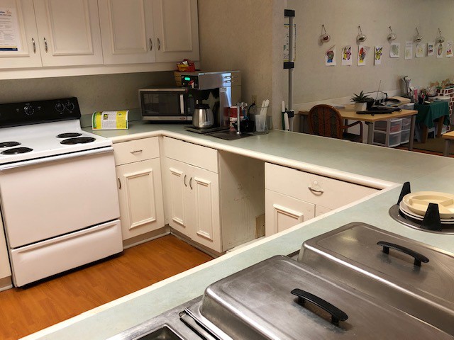 A cozy kitchen featuring a stove, microwave, and coffeemaker with ample countertop space and white cabinets.