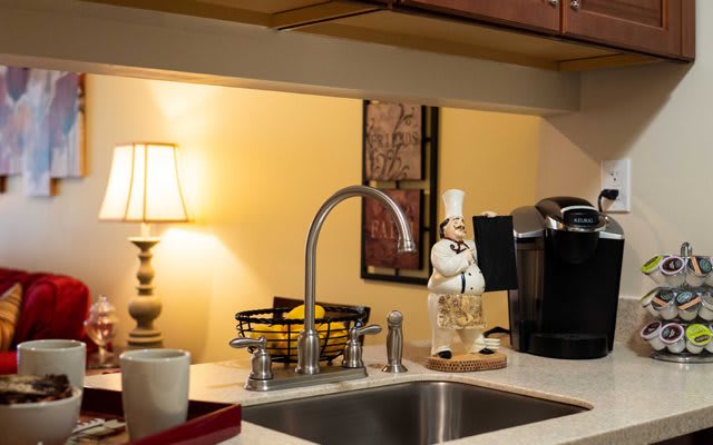 A cozy kitchen space with a sink, lamp, and coffee maker on the countertop.