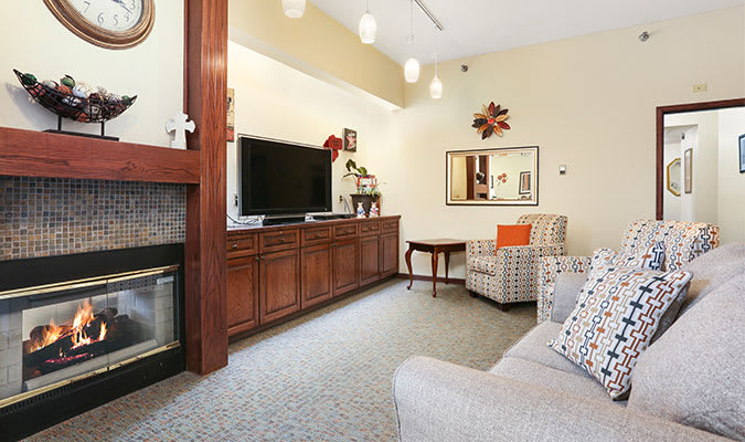 A cozy living room featuring a large television, fireplace, and comfortable seating.