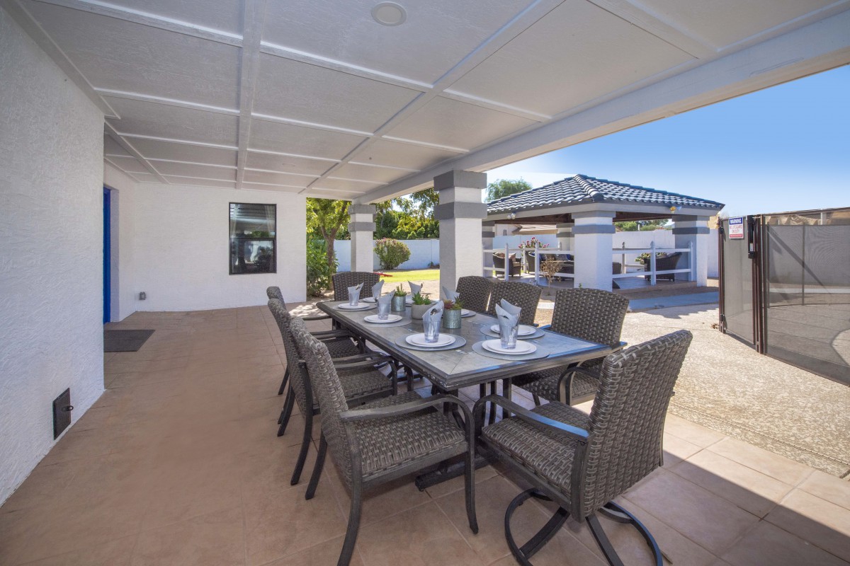 An elegant outdoor dining area with a modern table setting under a covered patio.