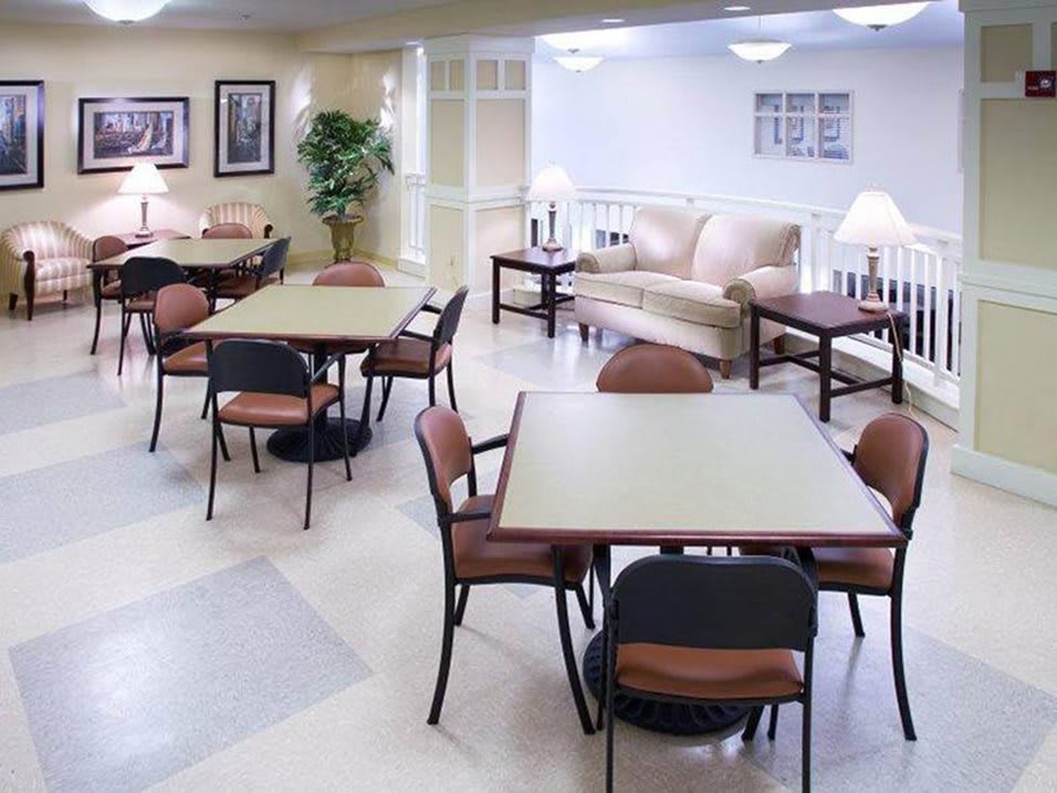 A comfortable lounge area with tables and chairs, well-lit by lamps.