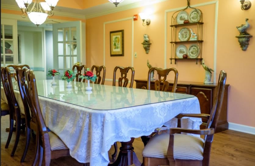 A well-decorated dining room featuring a long table with a white tablecloth, surrounded by wooden chairs.