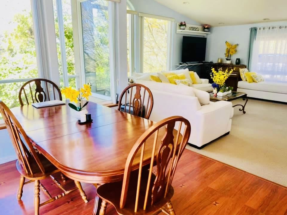 A bright and airy open-concept living and dining area with a wooden table, white sofas, and touches of yellow decor.