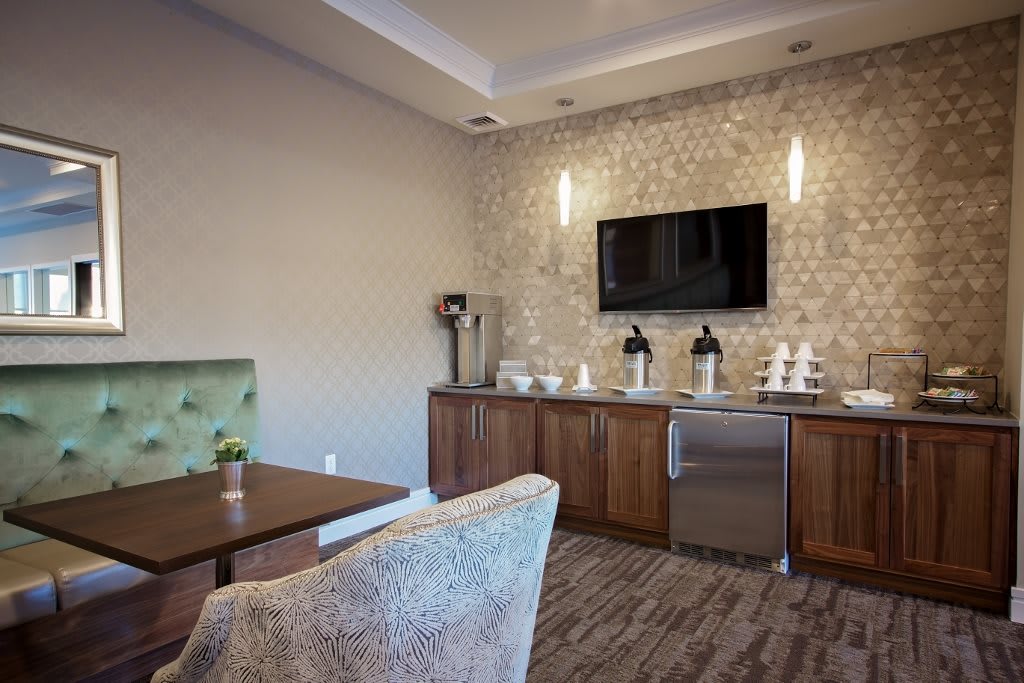A modern lounge with a coffee station and TV, featuring stylish decor and comfortable seating.