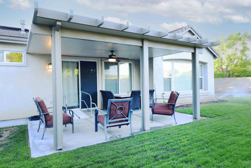 A cozy patio with outdoor seating under a covered area, surrounded by a well-kept backyard.