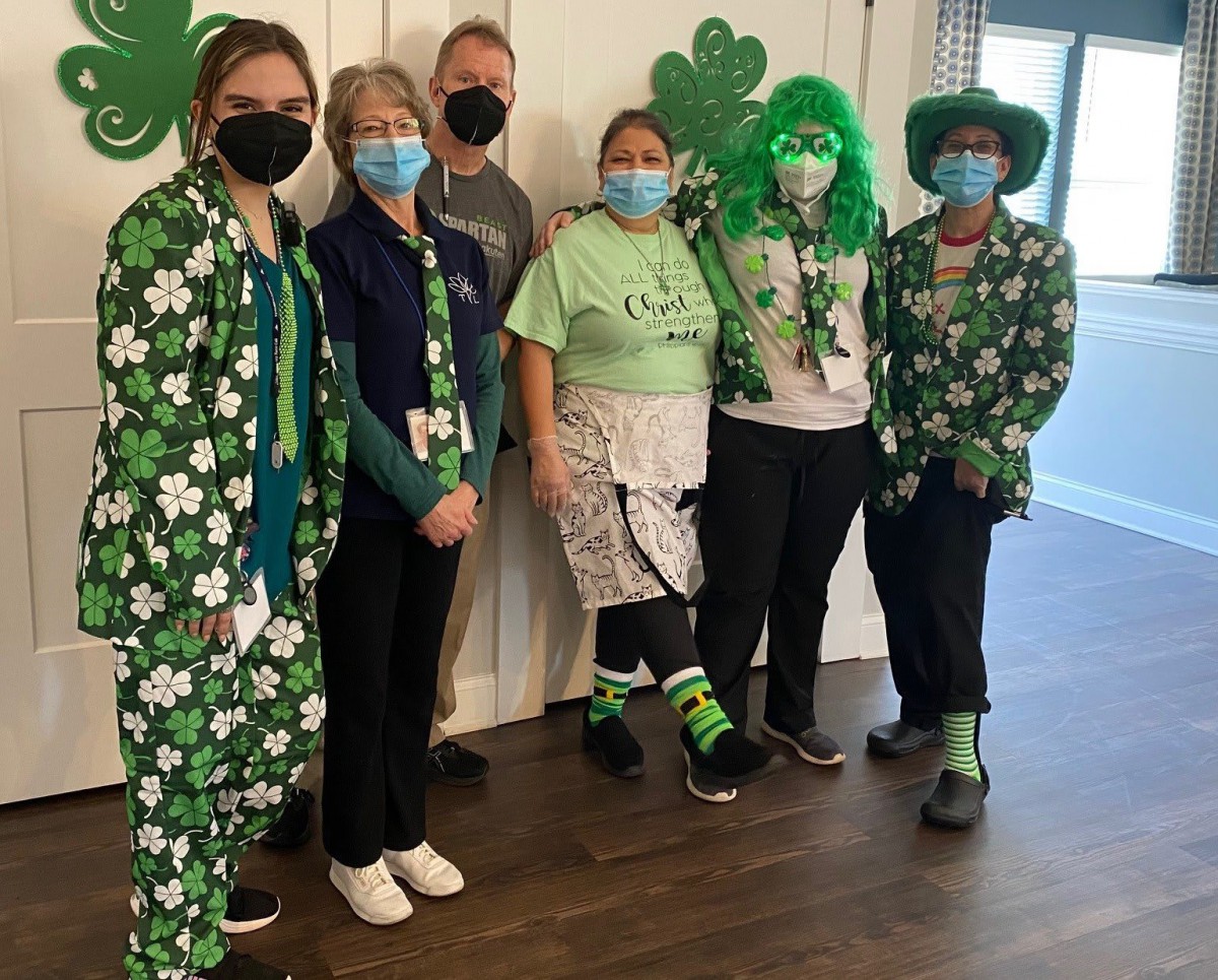 A group of people dressed in festive St. Patrick's Day attire, featuring green and shamrock-themed costumes.