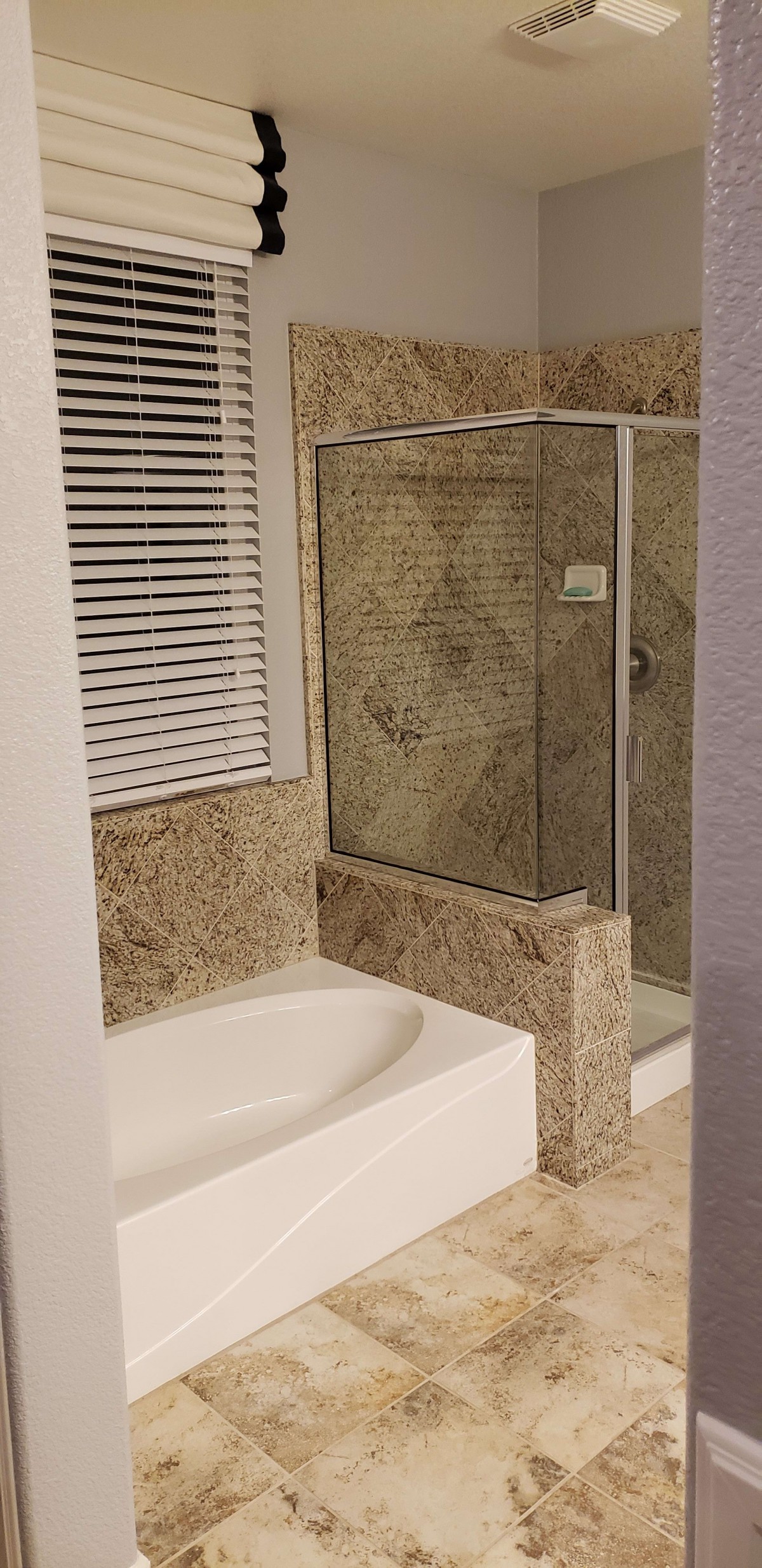 A modern bathroom featuring a bathtub and a glass-enclosed shower with tiled walls.