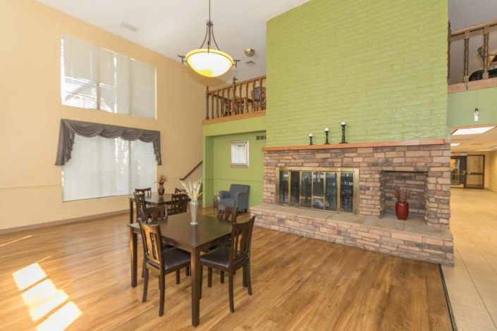 Spacious dining area with a brick fireplace and green accent wall.