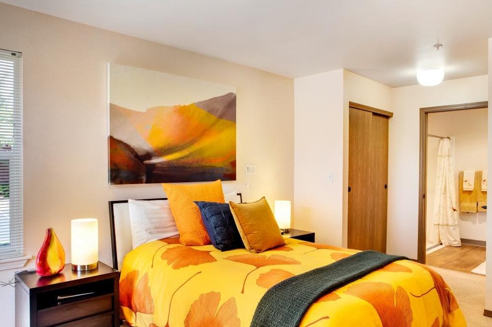 A modern bedroom with orange bedding and artistic wall decor.