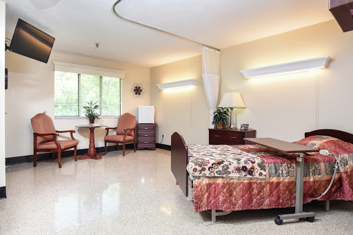 A well-lit and clean hospital patient room equipped with a bed, seating area, and window.