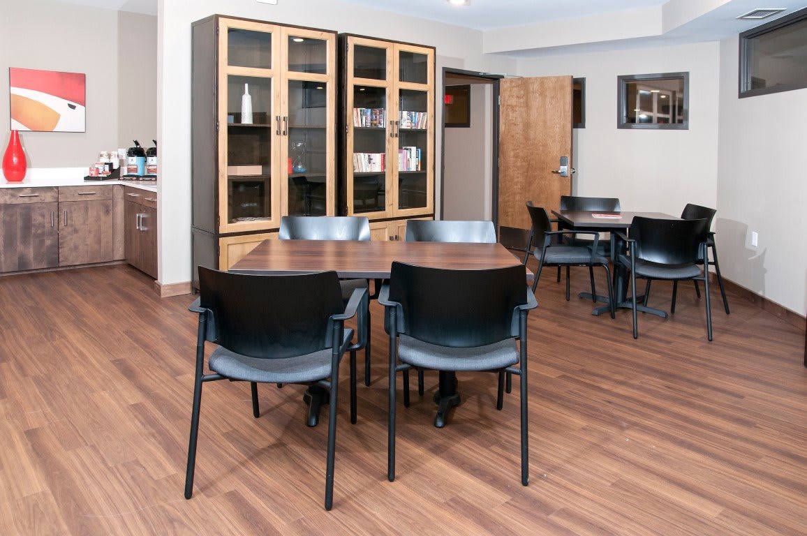 A cozy indoor dining area with tables, chairs, and a wooden cabinet.