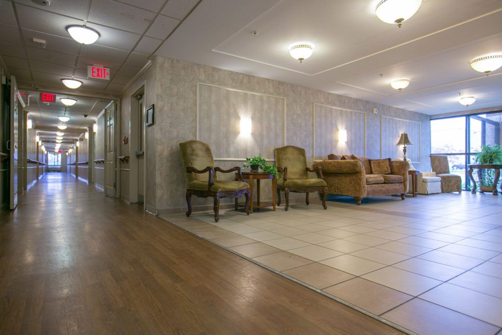 A well-lit hallway with a seating area, featuring comfortable chairs and decorative lights.