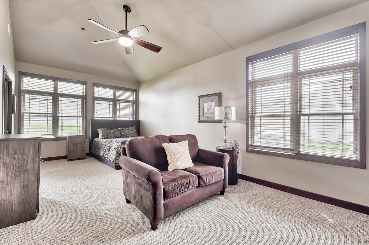 A cozy bedroom with a sofa and bed, featuring large windows and a stylish lamp.