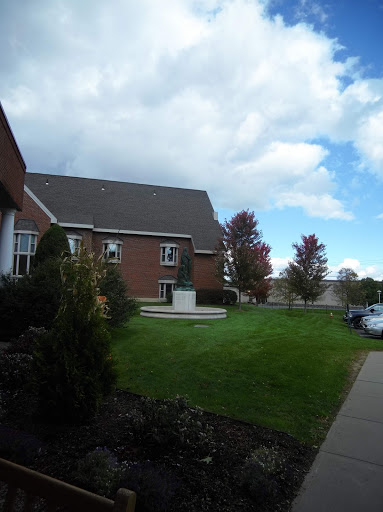 A picturesque view of a building surrounded by green grass and trees under a cloudy sky.
