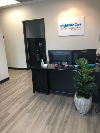 A clean and modern reception area of BrightStar Care with a workstation and indoor plant.