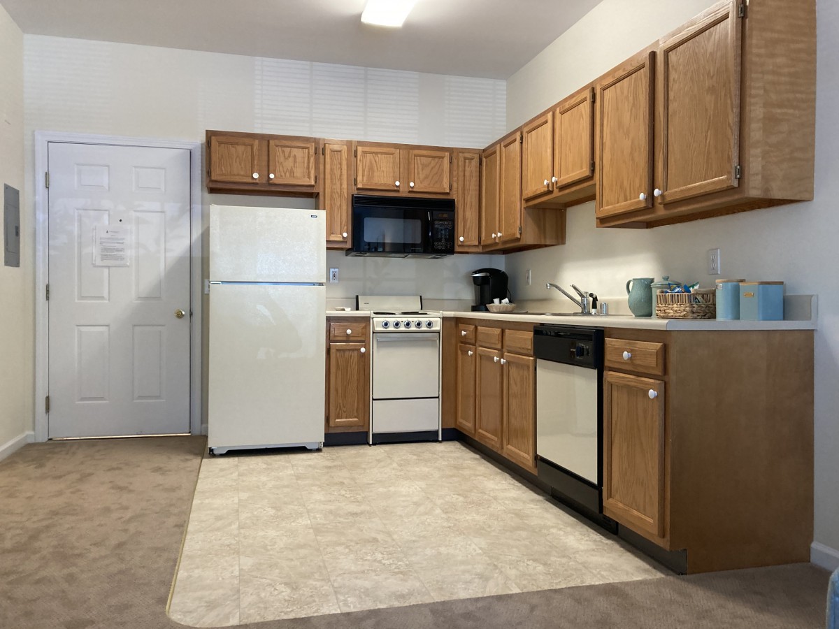 A modern kitchen with wooden cabinets, a refrigerator, stove, microwave, and dishwasher.