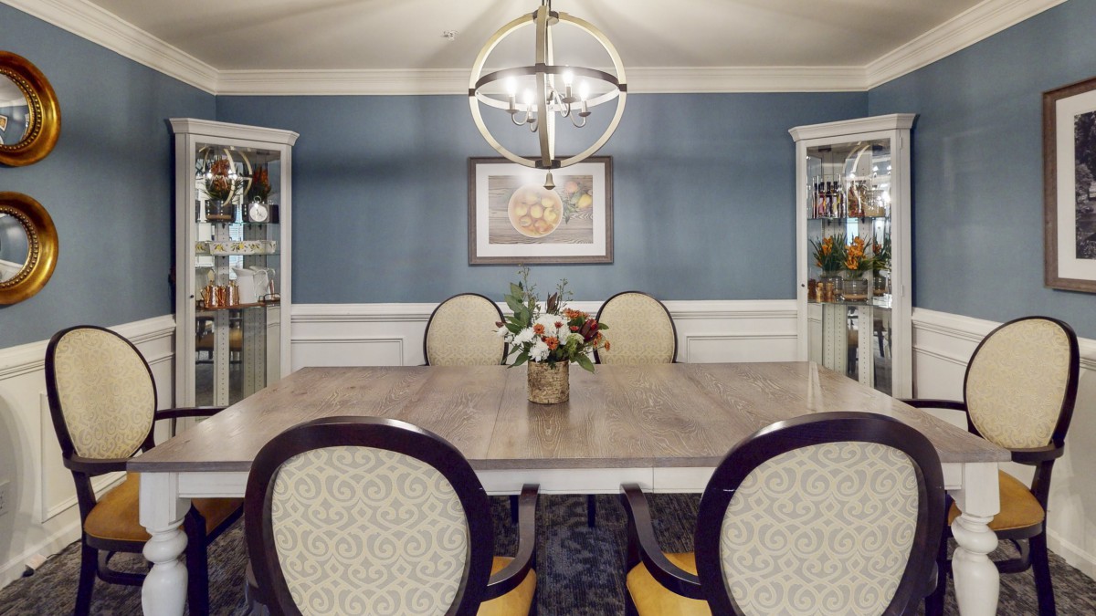 A well-decorated dining room featuring a central table, upholstered chairs, and a modern chandelier.