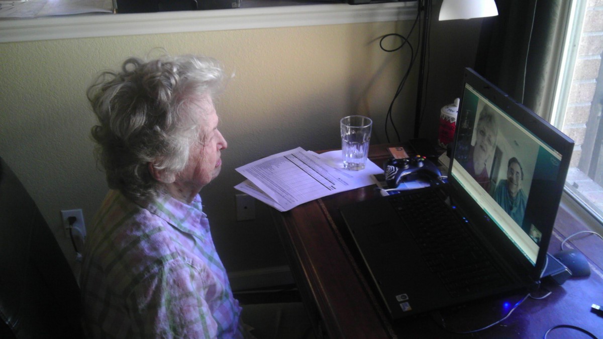 An elderly person sitting at a desk, using a computer.