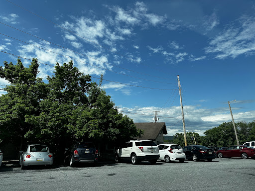 A view of a parking lot with various cars under a partly cloudy sky.
