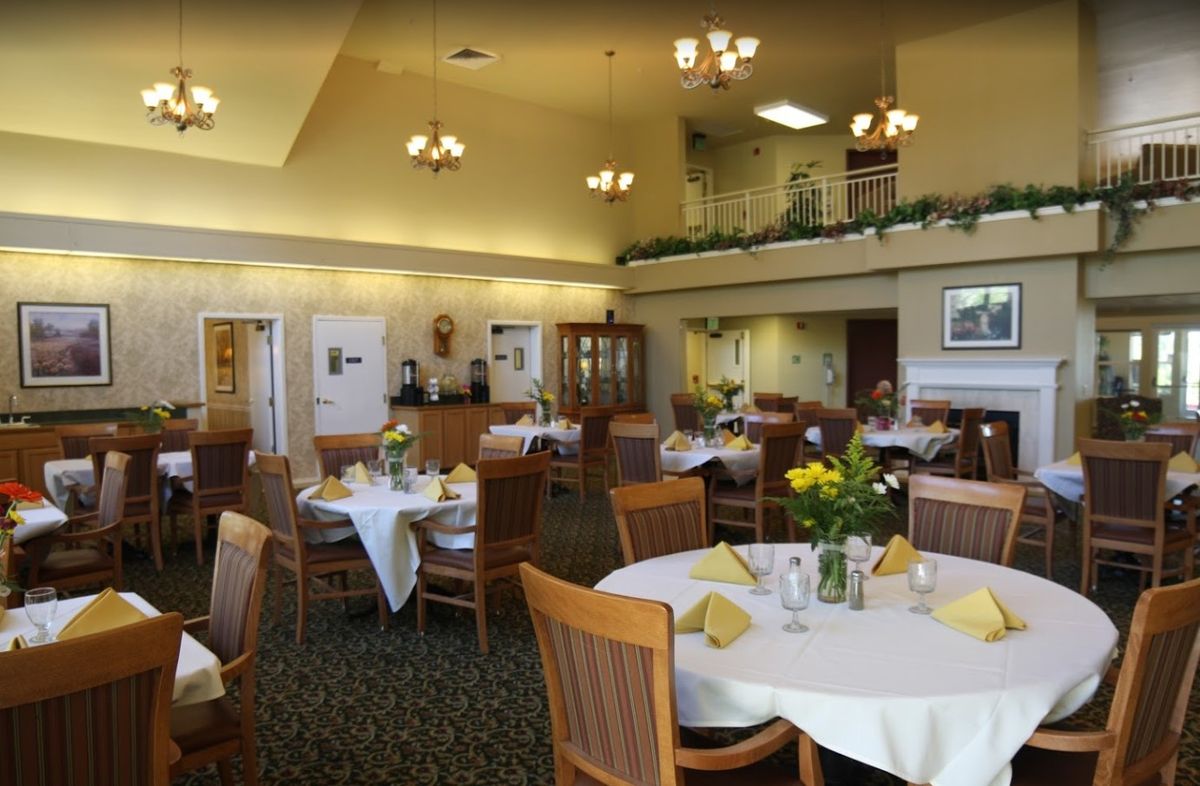 A well-lit dining area with neatly arranged tables and chairs, featuring elegant decor.