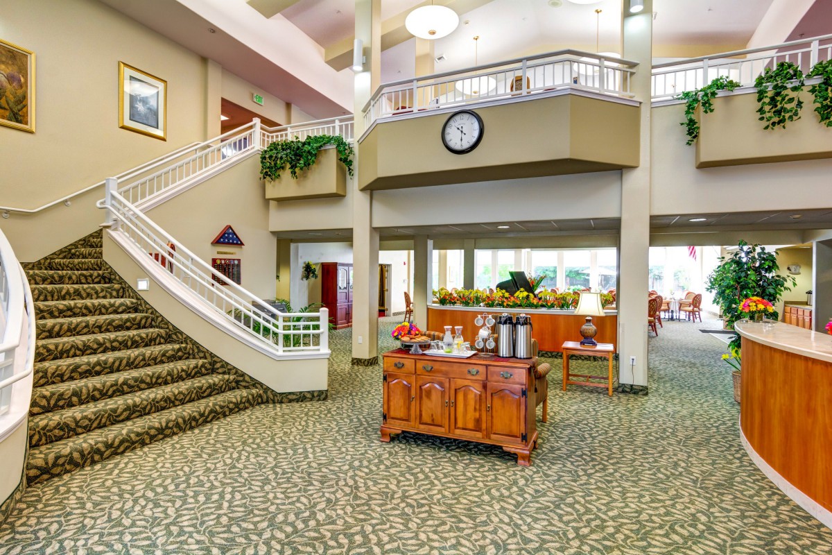 A spacious and well-lit lobby featuring a grand staircase and elegant decor.