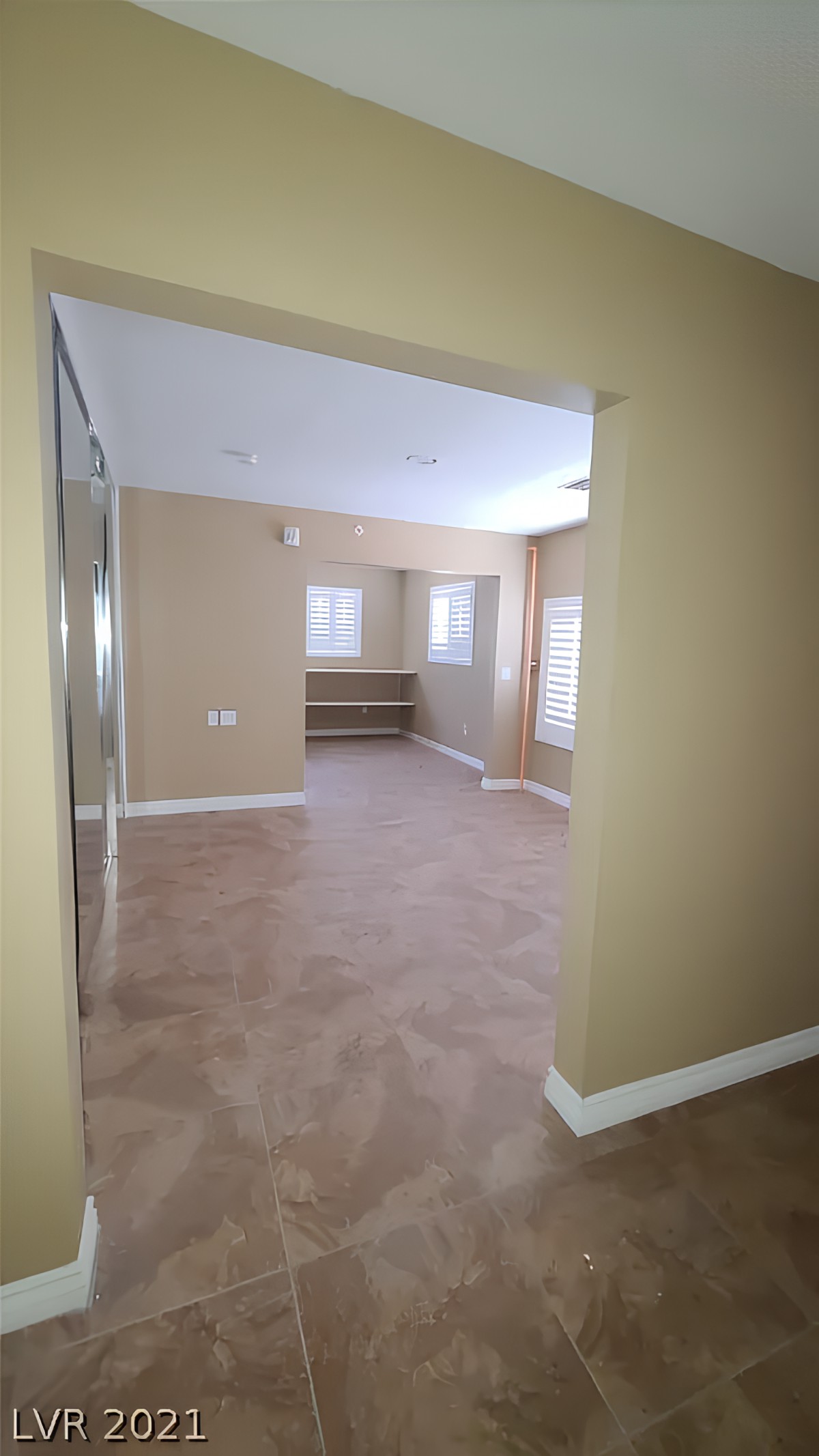 A spacious empty room with carpet flooring and several windows providing natural light.