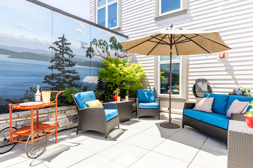 A stylish outdoor patio with comfortable seating, an umbrella for shade, and beautiful greenery.