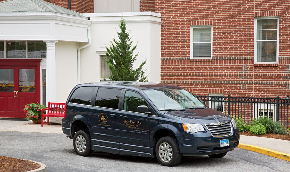 A blue minivan parked next to a brick building with a tree nearby.
