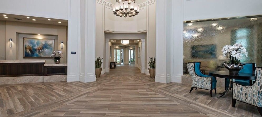 A luxurious hallway with a chandelier and wooden flooring, adorned with plants.