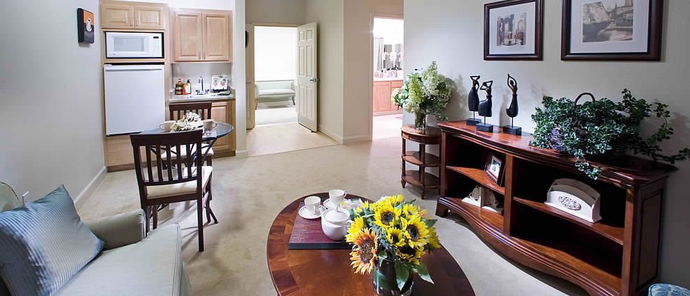 A cozy living room with a view into the kitchen, featuring a wooden coffee table and vibrant sunflowers.
