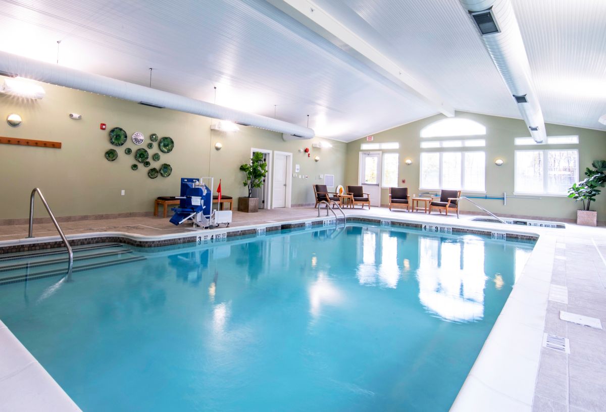 An inviting indoor swimming pool with seating and natural lighting.