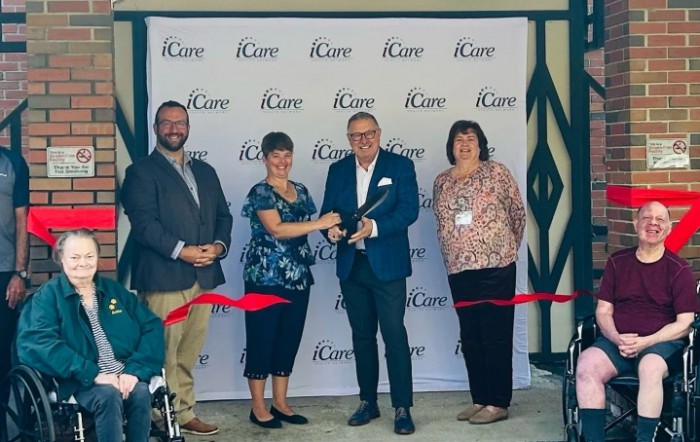 A group of people participate in a ribbon-cutting ceremony at an event.