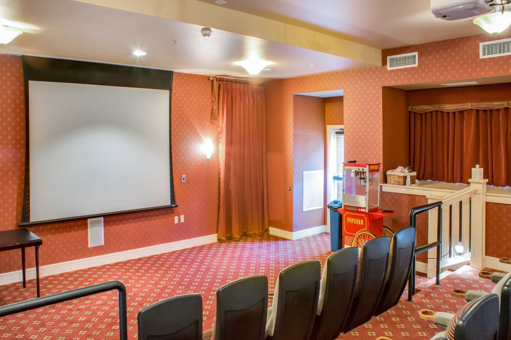 A cozy home theater setup with rows of seats, a large screen, and a popcorn machine.