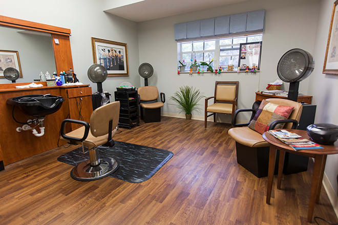 Interior view of a hair salon with chairs, mirrors, and wooden flooring.