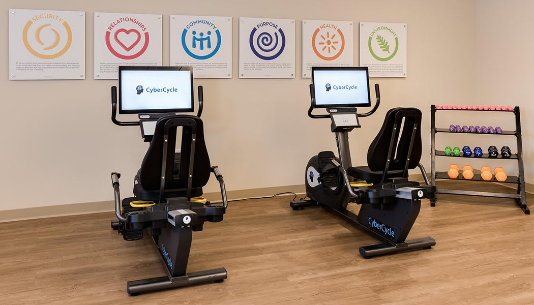 Two stationary exercise bikes in a gym setting with digital displays.
