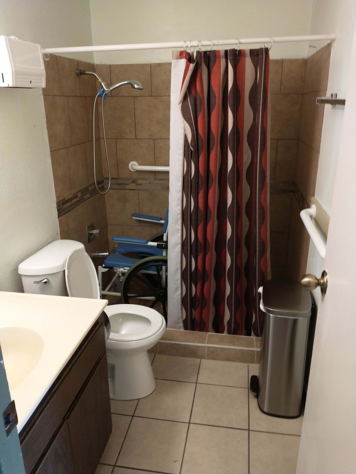 Wheelchair-accessible bathroom with a shower area and safety features.