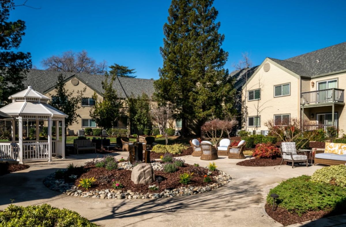 A well-maintained garden with a pathway and benches in front of a residential building.
