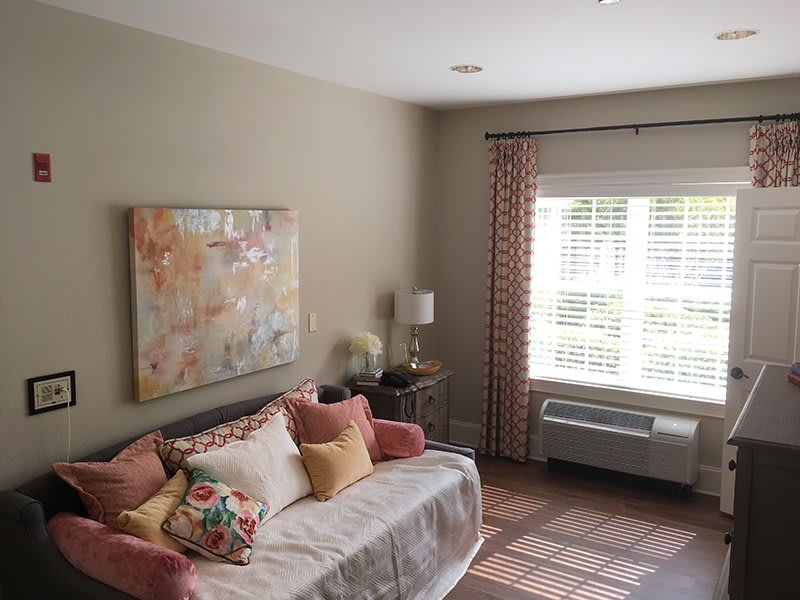 A cozy living room with a sofa, colorful pillows, and abstract artwork on the wall.