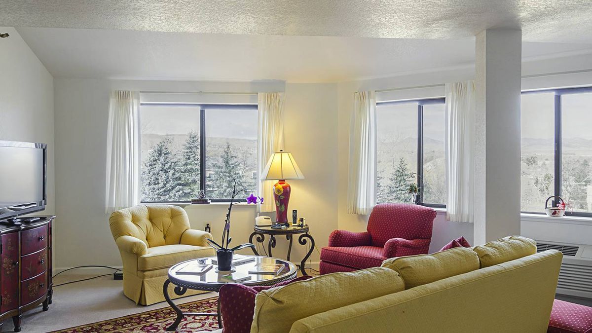A cozy living room with colorful furniture and large windows allowing natural light.