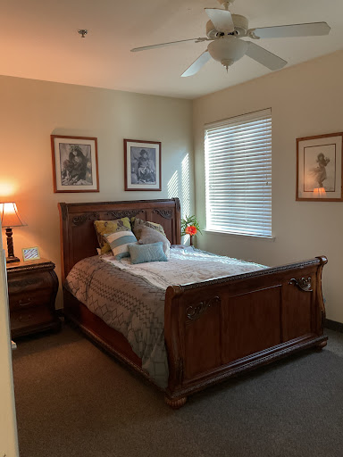A cozy, well-decorated bedroom featuring a wooden bed, bedside lamp, and framed artwork.