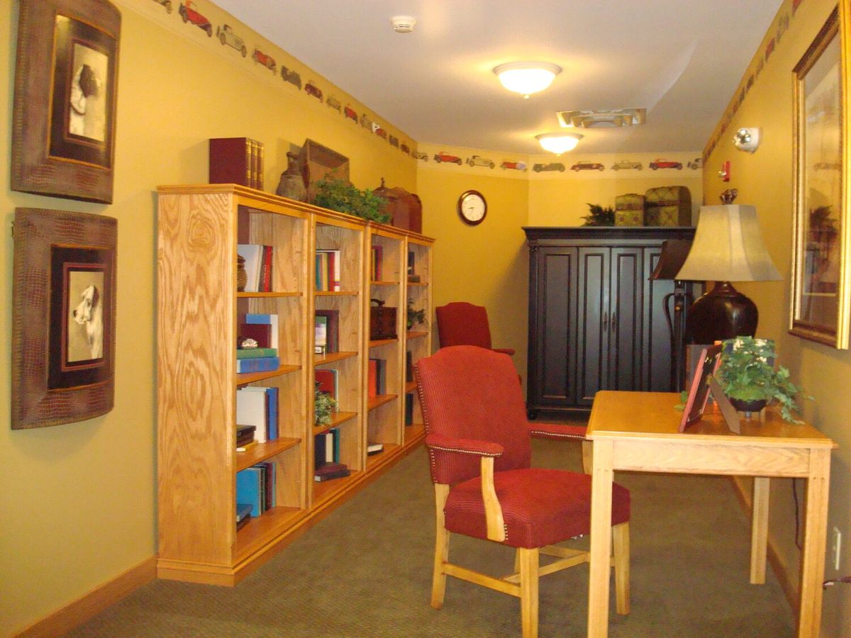 A cozy indoor library space with bookshelves, a desk, and chairs for reading.